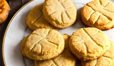 A pile of sweet potato biscuits sitting in a large white fluted bowl. This is the designated pinterest pin.