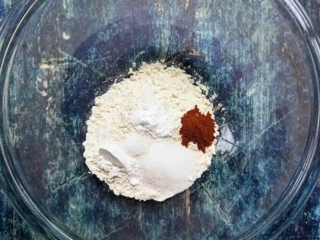 Blueberry Buttermilk Pancakes Process Step 1b A pile of the dry ingredients in a large glass bowl on a blue background.