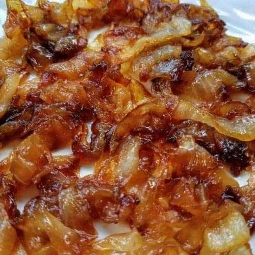 Close-up of finished caramelized onions on a white plate.