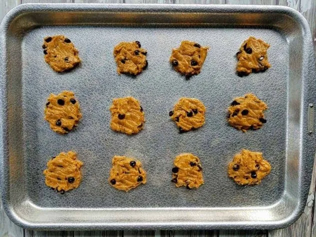 Pumpkin chocolate chip cookies on a textured aluminum baking sheet prior to going in the oven.