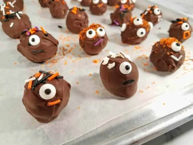 Chocolate Peanut Butter Balls Process Step 6 Halloween decorated chocolate peanut butter balls sit on a wax paper lined baking tray after refrigeration to harden chocolate.