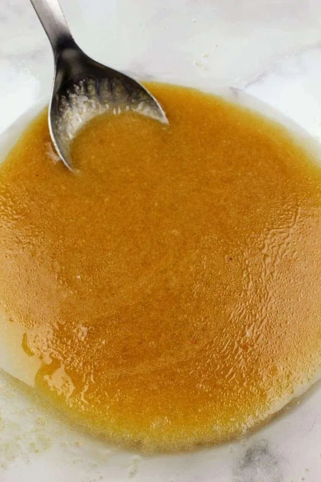 Dairy Free Chocolate Chip Cookies Process Step 1 Extra light olive oil, applesauce, vanilla extract, light brown sugar, granulated sugar, Kosher salt, and baking soda all mixed together in a large glass bowl with a stainless steel mixing spoon.
