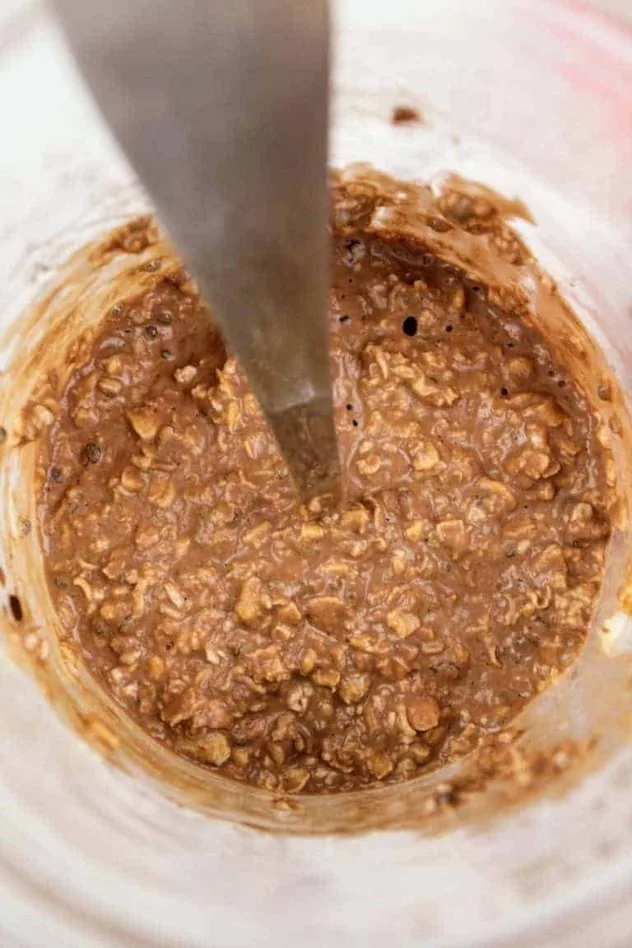 Chocolate Overnight Oats Process Step 3a Top view of chocolate overnight oats after all the ingredients have been mixed together in a glass mason jar, but before it is put into the fridge. The spoon that was used to mix everything together is left in the jar.