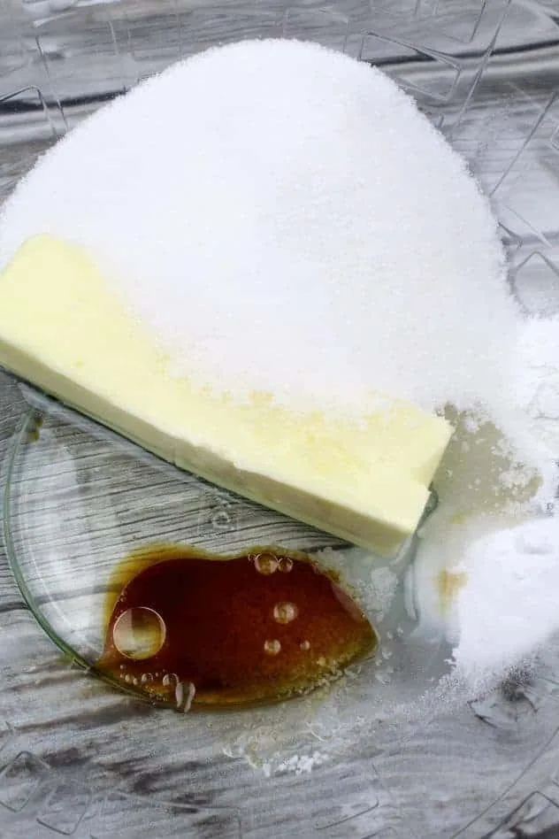 Gluten-Free Ricotta Cookies Process Step 1a Butter alternative, granulated sugar, extra light olive oil, vanilla extract, Kosher salt, baking soda, and baking powder sit in a large glass bowl on a wood plank background.