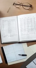 On the right is a black hand calculator with red buttons and on the left is a pen. Both items lay on insurance paperwork and healthcare bills. Below the picture are the words 'Fixing US Healthcare' followed by a dark red horizontal line, and then the words 'The Cost of Medicare For All vs. Private Insurance. Below that, is a red heart with a bandaid on it. At the top of the pin are the words 'The Panicked Foodie' with a black mixing bowl stamped with a red heart filled with white sugar cubes.