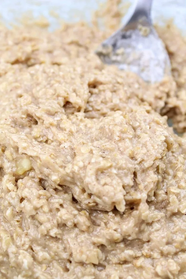 Addition of flour to the mixture to make a dough in a large glass mixing bowl with a stainless steel mixing spoon in the upper right.