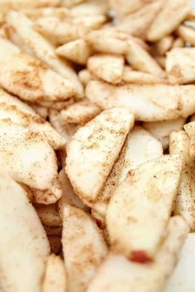 A close-up of apple slices coated with gluten-free flour and apple pie spice.