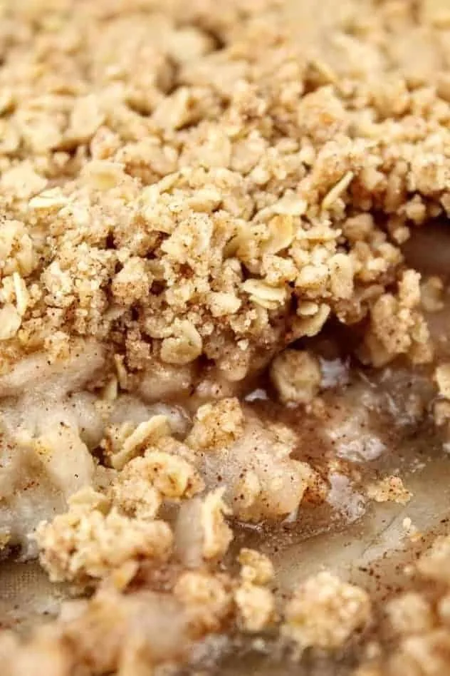 A close up head on photo of the vegan gluten-free apple crisp right after it comes out of the oven. A few scoops have been removed, to clearly show the two layers: filling and topping.
