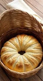 A close up of the inside of a homemade crescent roll. In the background are the rest of the rolls sitting on a wire cooling rack. This is the vertical image. At the top of the image are the words 'The Panicked Foodie,' with the i's colored red and dotted with red hearts. At the end is a black mixing bowl with a red heart on it that contains three sugar cubes.